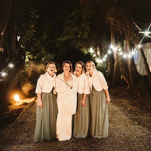 Four happy women celebrate at an outdoor wedding, creating a warm and elegant atmosphere under string lights.
