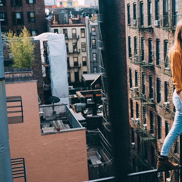 A woman stands on a rooftop in an urban cityscape, enjoying the view and the relaxed atmosphere.
