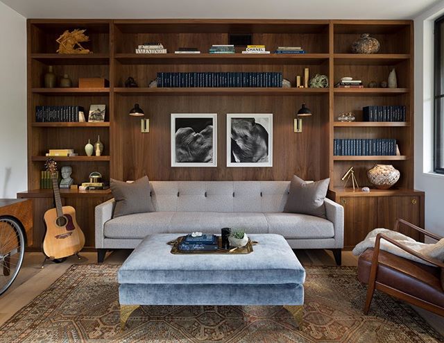 A stylish living room featuring a sofa, books, guitar, and ottoman, creating a calm and harmonious atmosphere.