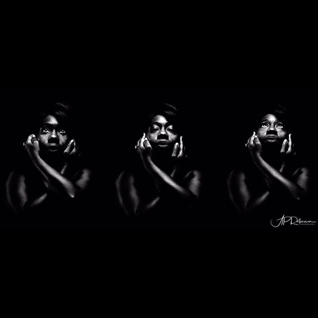 Monochrome artistic self-portrait of a woman with emotional expression against a dark backdrop.