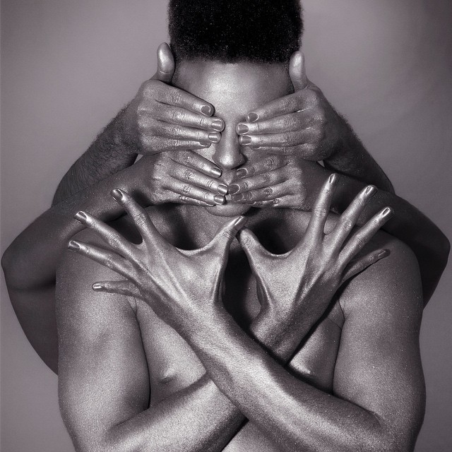 A monochrome artistic image features a man covered in hands conveying emotions and self-expression.