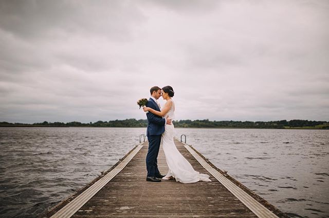 A bride and groom embrace on a pier at their wedding. A romantic, intimate moment.