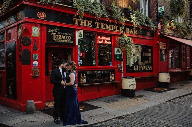 A loving couple embraces in front of the iconic Temple Bar in Dublin, Ireland.