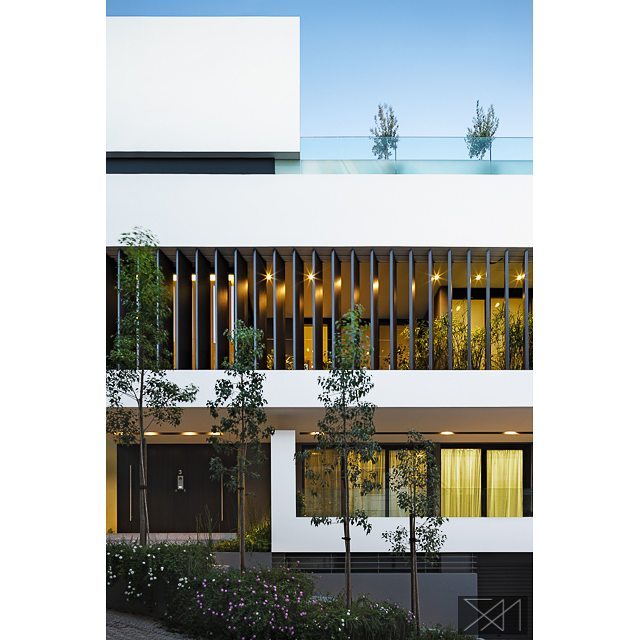 Modern home architecture featuring a clean, minimalist facade with trees in the foreground, showcasing sleek design for real estate.