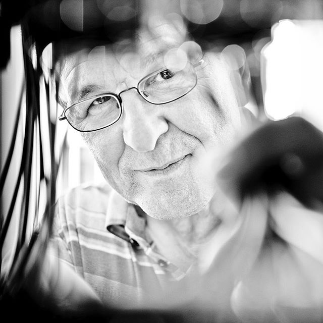 A black and white close-up portrait of a man with glasses looking directly at the camera.