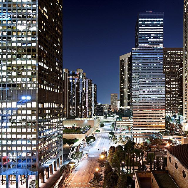 Cityscape at night featuring skyscrapers and an empty street, conveying a calm and tranquil urban scene.