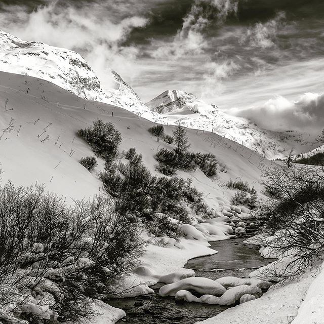 Monochrome scenic view of a mountain river in winter, showcasing a snow-covered landscape.