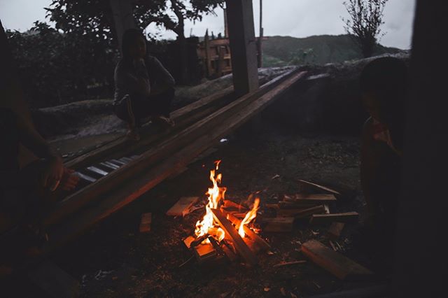 A cozy campfire crackles as people gather in the dark, creating a scene of relaxation and contemplation.