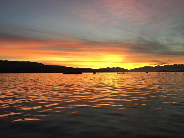 A picturesque sunset over a serene lake with distant mountains creates a peaceful and scenic landscape.