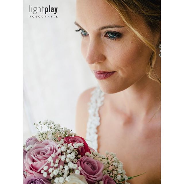 A woman with a bouquet of roses looking off camera.