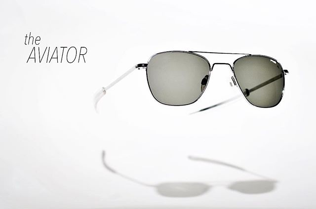 Stylish aviator sunglasses floating on a white surface, casting soft shadows in a clean, modern composition.