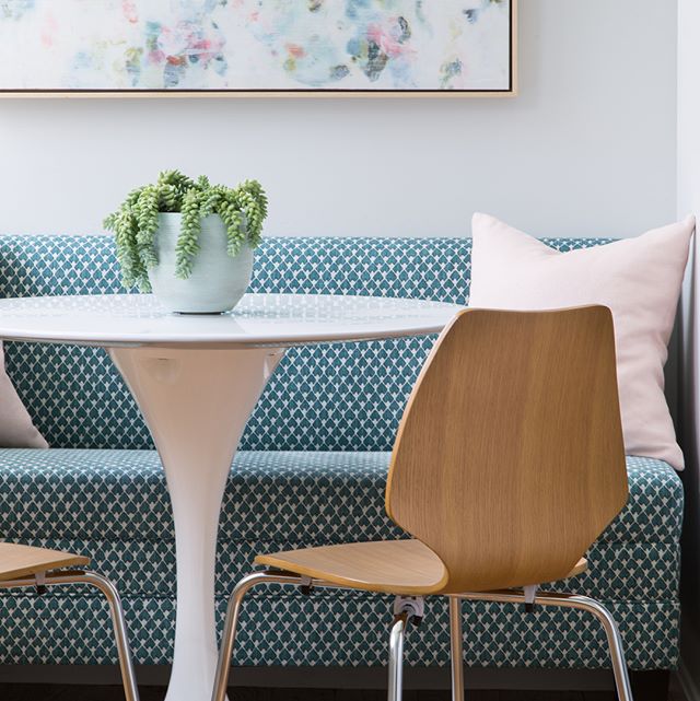 A cozy dining nook featuring a round table, stylish chairs, and a patterned banquette with soft cushions.