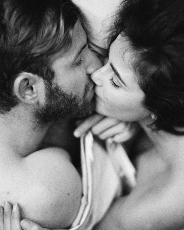 An intimate black and white shot of a couple sharing a tender kiss in a soft, dreamy embrace.