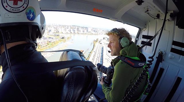 A photographer in a helicopter captures a city view, blending adventure and urban exploration.