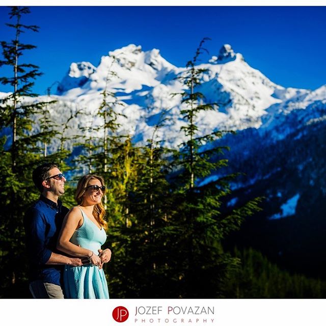 A happy couple embraces in front of a scenic mountain backdrop.