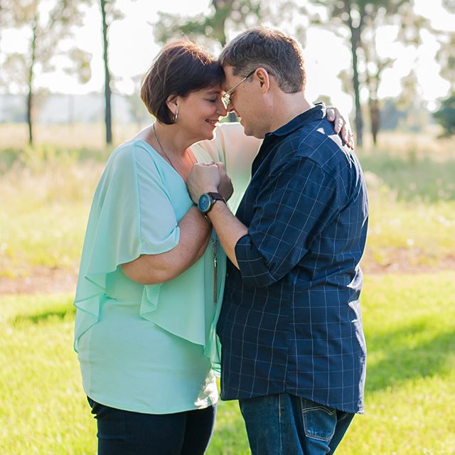 A loving couple embraces outdoors in a sunny park, radiating happiness and tenderness.