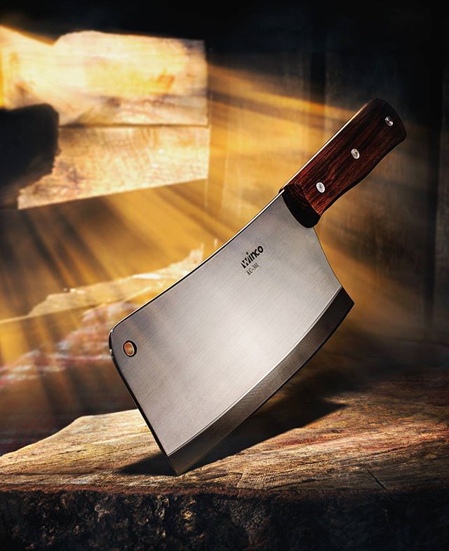 A close-up of a Winco cleaver, essential kitchenware, on a wooden surface, enhanced by soft artificial lighting.