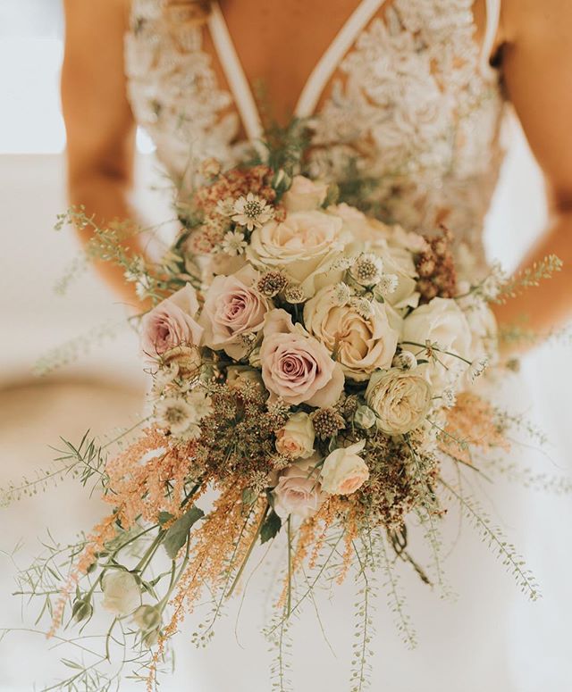 A bride holds a soft, romantic bouquet of roses at her wedding, creating a dreamy and intimate atmosphere.