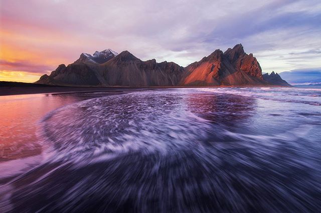 A breathtaking ocean view with mountains in the background at dusk, showcasing tranquil scenery perfect for travel destinations.