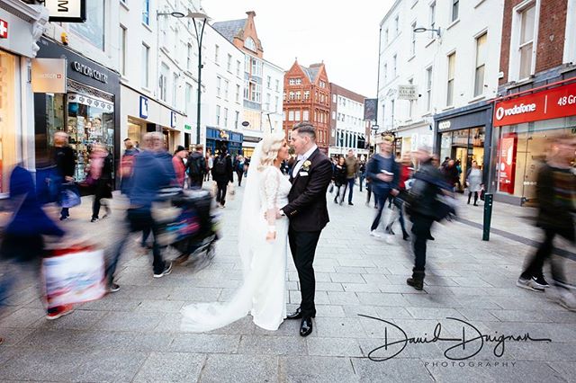 A bride and groom embrace in the middle of a bustling city street on their wedding day.