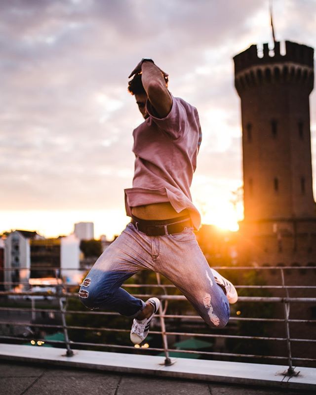 Man jumping mid-air on a rooftop with cityscape and sunset views, embodying freedom and vitality.
