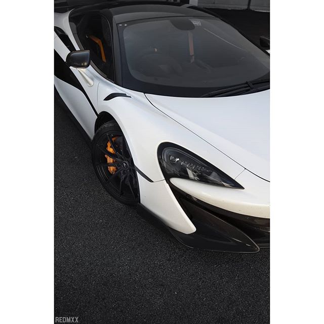 Close-up of a sleek white McLaren supercar, showcasing its modern design and powerful presence on the asphalt.