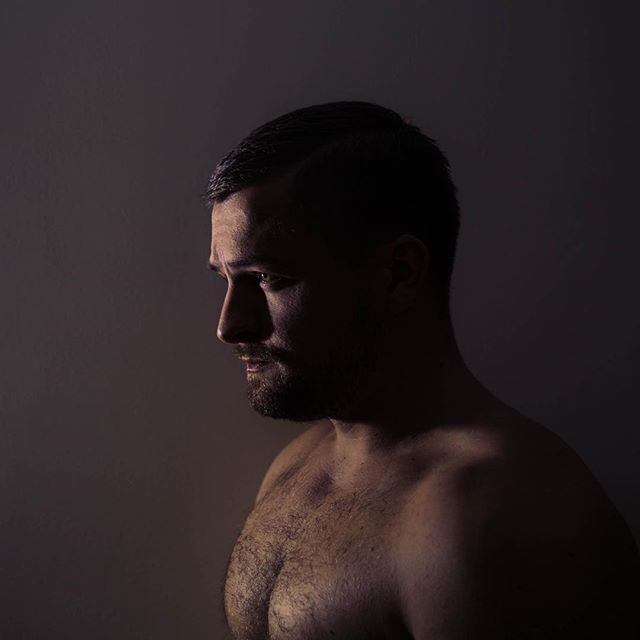 A shirtless man in moody lighting. Studio shot of a male with a dramatic atmosphere.