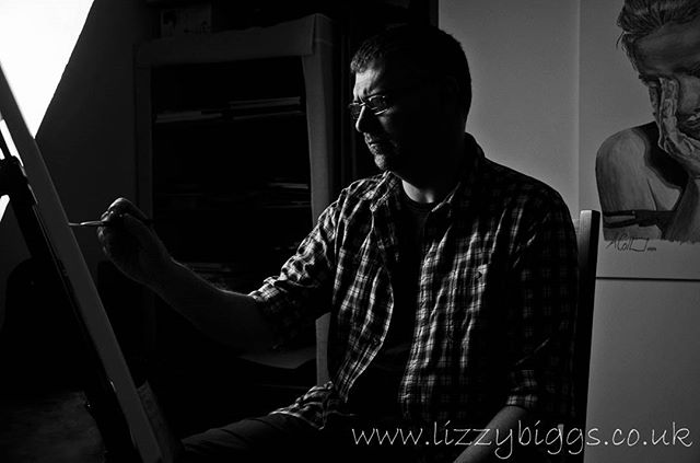 A man painting in black and white, showcasing the creative process in an art studio setting.