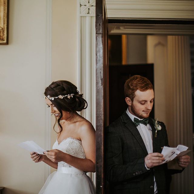 A bride and groom standing back to back, reading letters before their wedding ceremony.