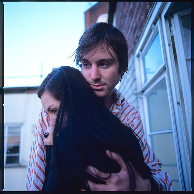 A couple embraces on a balcony, showcasing an intimate and loving moment with soft, dreamy lighting.