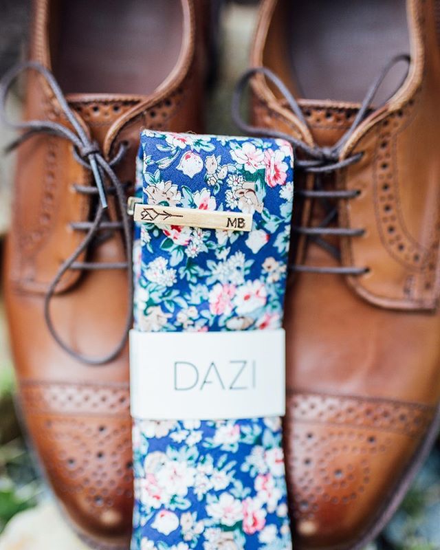 Groom's brown shoes and floral tie are displayed, capturing wedding details and style.
