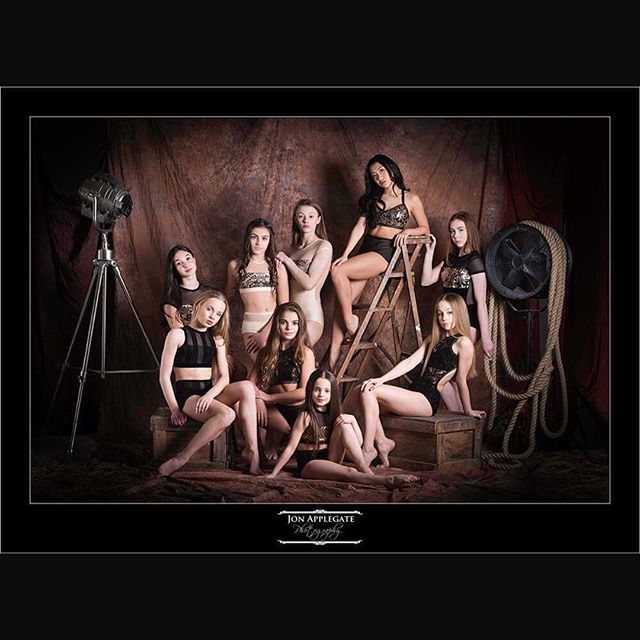 A group of confident young dancers pose in a vintage-style studio setting.