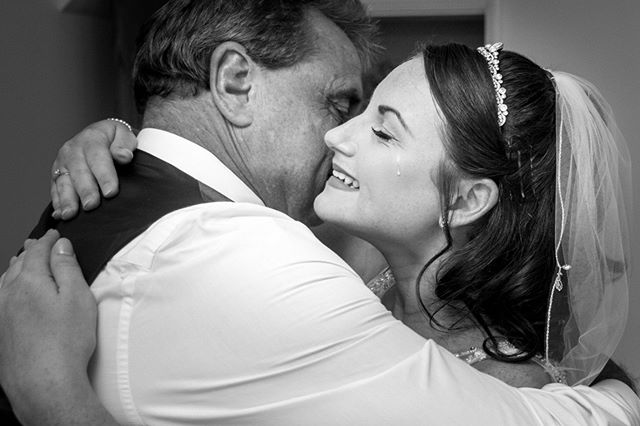 A touching black and white photo capturing an emotional moment between a bride and her father on her wedding day.