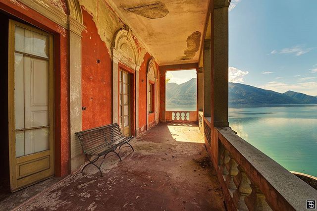 A rustic balcony overlooks a tranquil lake and majestic mountains in this scenic architectural vista.