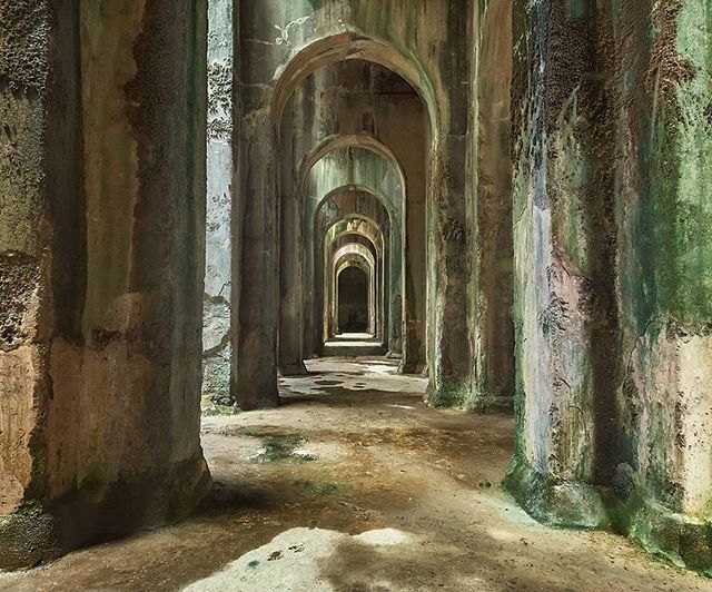 A long corridor of arched pillars creates a tunnel effect in this aged, architectural interior.
