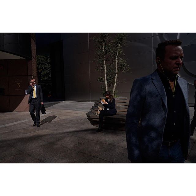 People in business attire walk and relax in an urban environment on a city street.