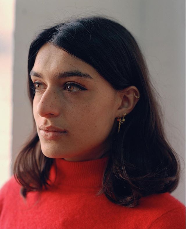 A brunette woman with freckles gazes softly to the side in a warm-toned portrait.