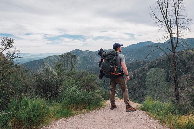 A lone hiker with a backpack gazes over a mountainous landscape, embodying adventure and outdoor exploration.