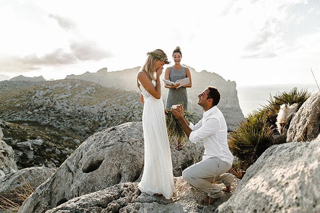 A man proposes to a woman on a mountain during a wedding ceremony with an officiant.