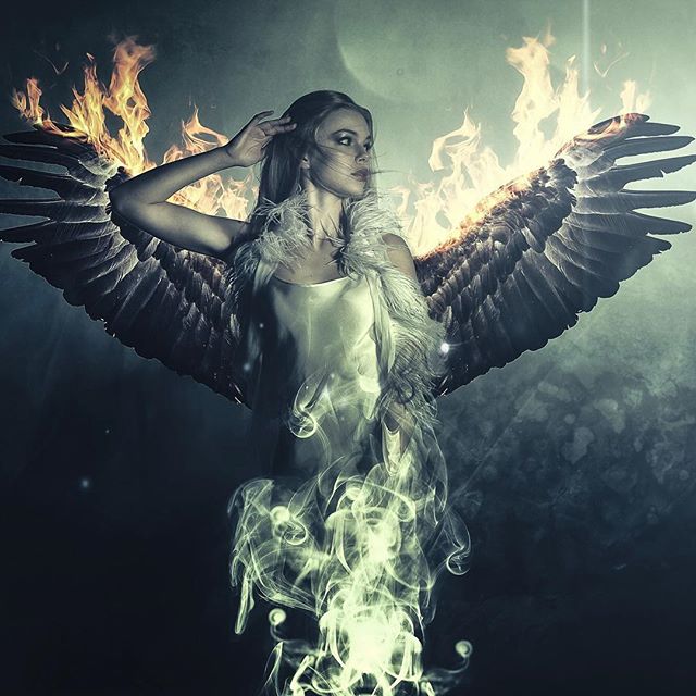 A woman with wings of fire and smoke creates a mystical angelic figure in a dreamy fantasy art scene.