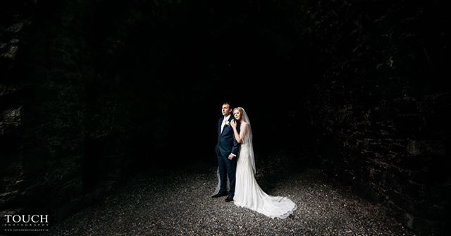 A bride and groom stand together in a softly lit outdoor forest location on their wedding day.