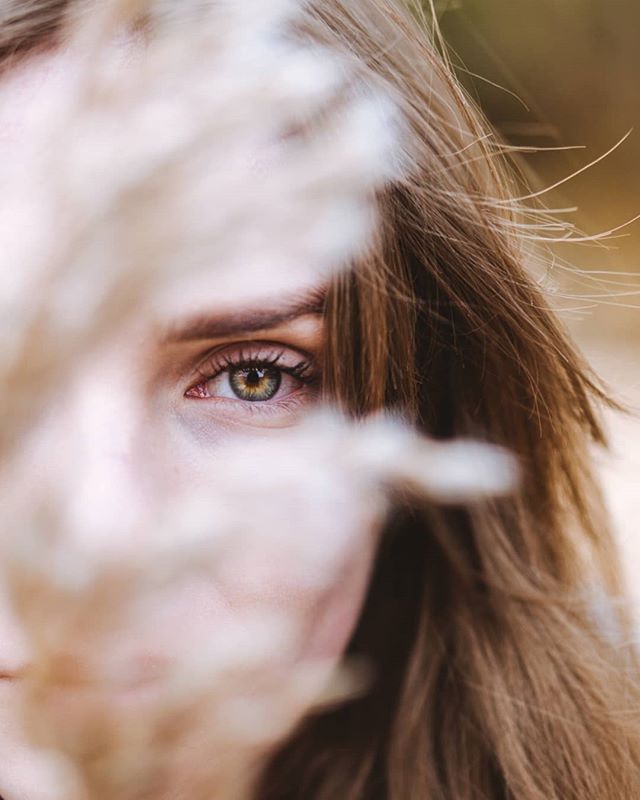 A close-up of a woman's face, with her eye in focus and soft, natural light. A dreamy and intimate portrait.