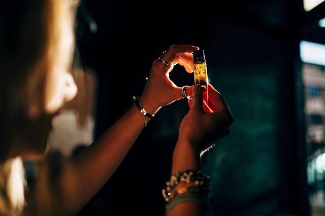 Woman holding a bottle of essential oil, showcasing a wellness product in soft, warm lighting.