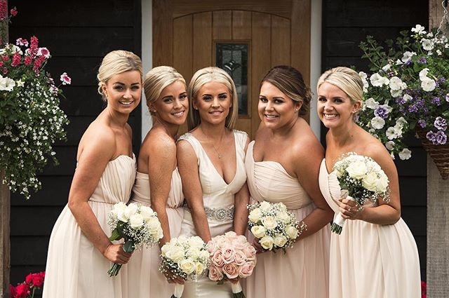 A bride and her bridesmaids pose with bouquets at an elegant wedding.