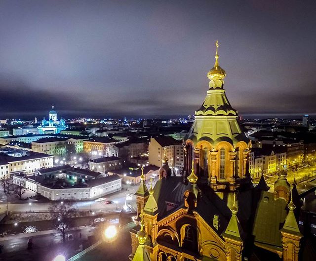 An illuminated cityscape at night features a prominent church dome in Helsinki, Finland.