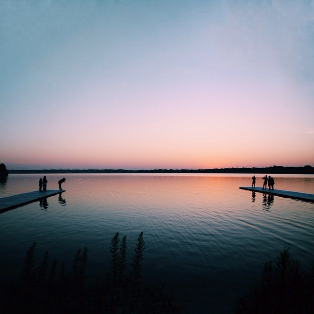 A group of people on docks enjoy a peaceful sunset over a calm lake, creating a serene and tranquil scene.