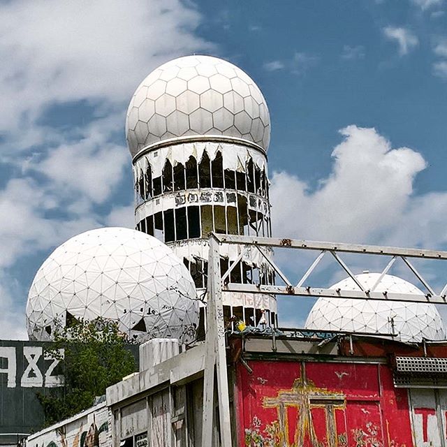 Teufelsberg's derelict radar domes stand against a cloudy sky in Berlin, showcasing Cold War history.