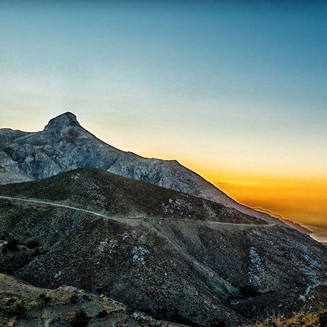 A scenic view of mountains and hills under a serene sky at sunset.