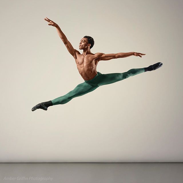 A male ballet dancer mid-air in a split leap, showcasing strength and grace in a fitness-focused image.