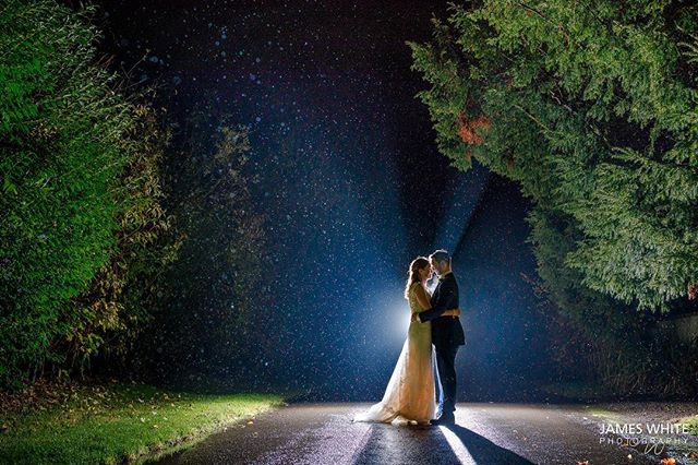 A bride and groom embrace on a road at night, bathed in soft backlighting, symbolizing love and new beginnings.